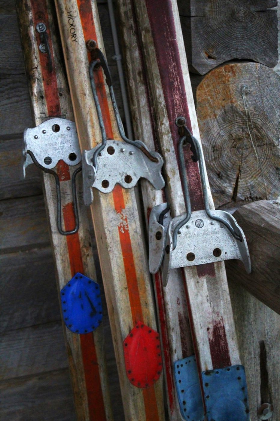 Weathered wooden skis with old cable bindings leaning against a log wall (stock placeholder)