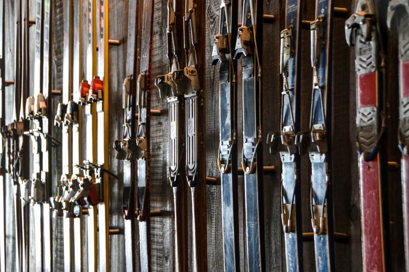 Vintage skis with cable bindings displayed on a weathered wooden wall (stock placeholder)