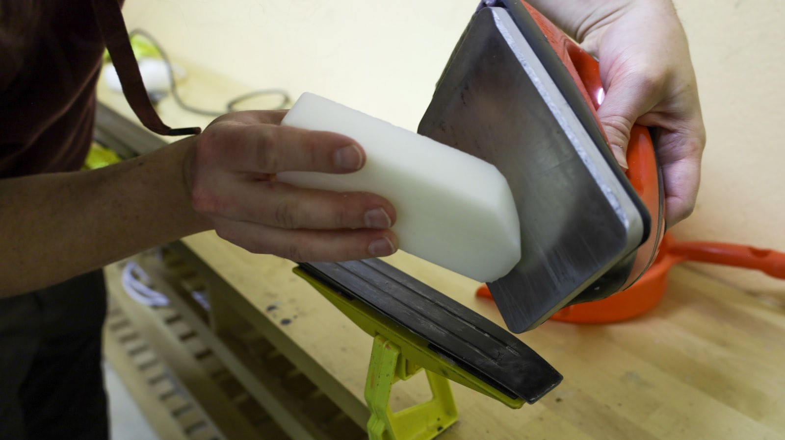 Wax block held against a hot iron over a ski vise (stock placeholder)